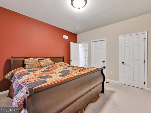 bedroom featuring baseboards, light carpet, and visible vents