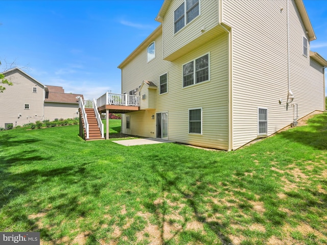 rear view of property with a lawn, a wooden deck, stairway, and a patio