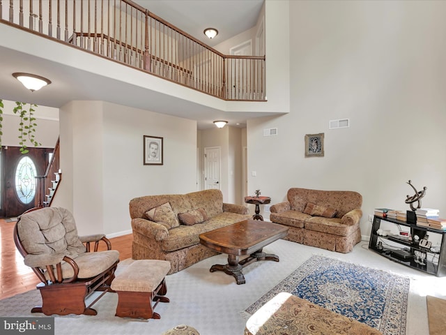 living area with baseboards, visible vents, stairs, and a towering ceiling