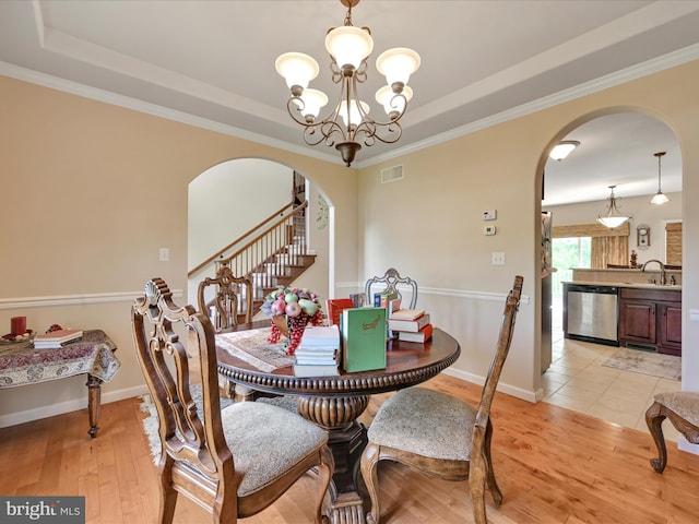 dining area featuring visible vents, arched walkways, and a tray ceiling