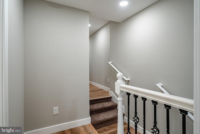 stairway featuring wood finished floors, recessed lighting, and baseboards