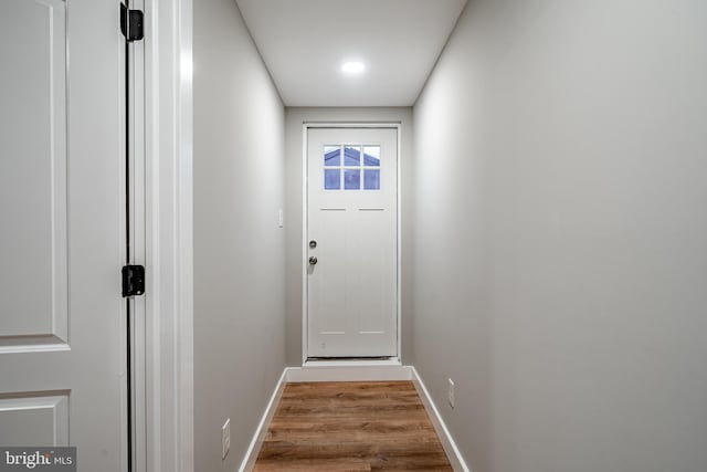 doorway with baseboards and wood finished floors
