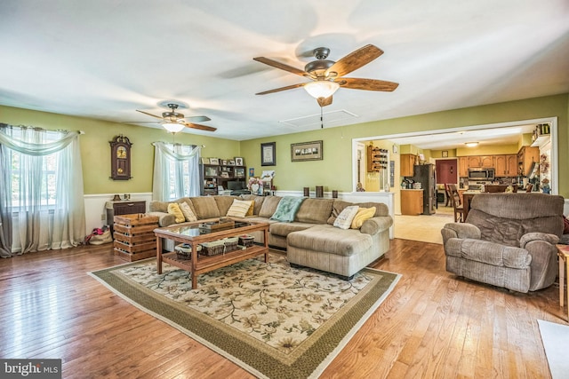 living room with a ceiling fan, light wood-style flooring, and attic access