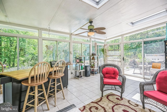 sunroom featuring a ceiling fan, a skylight, and a healthy amount of sunlight