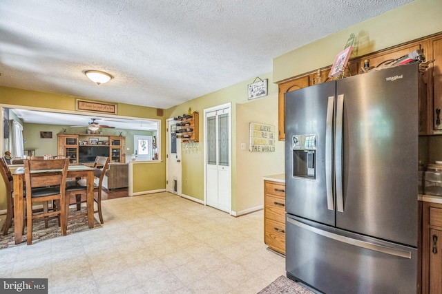kitchen with stainless steel fridge, brown cabinetry, and a textured ceiling