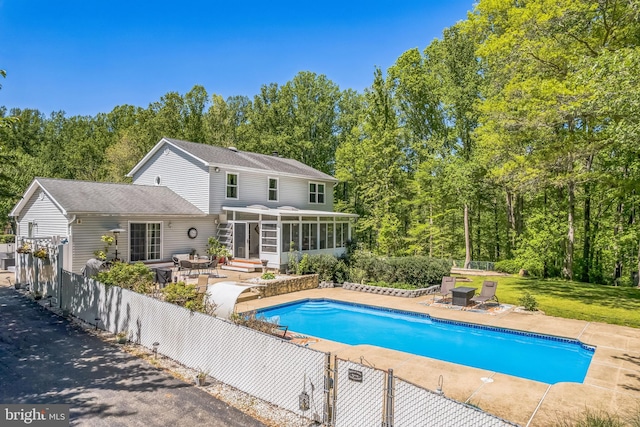 outdoor pool with a sunroom, fence, and a patio