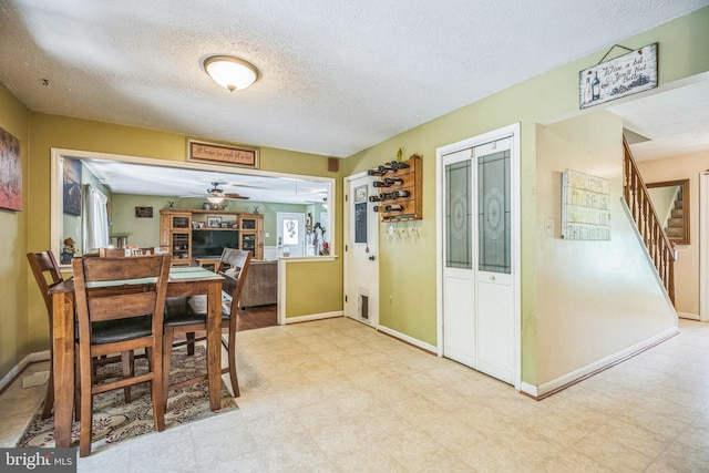 dining room featuring stairway, tile patterned floors, a ceiling fan, and a textured ceiling