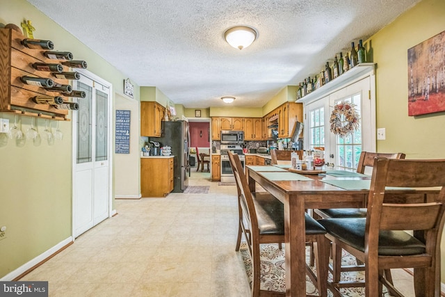 dining room featuring a textured ceiling, baseboards, and light floors