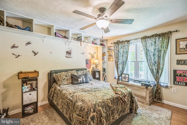 bedroom with baseboards, a textured ceiling, ceiling fan, and wood finished floors