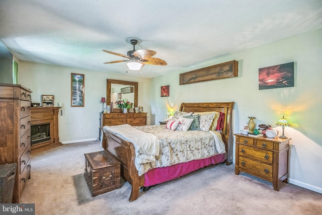 bedroom featuring baseboards, carpet flooring, a fireplace with raised hearth, and ceiling fan