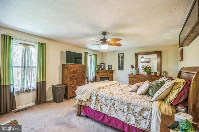 bedroom featuring ceiling fan, a textured ceiling, visible vents, carpet floors, and baseboards