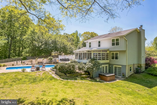 back of property with a hot tub, central AC, a sunroom, a fenced backyard, and a chimney