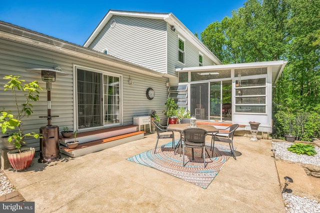 rear view of property with a sunroom, outdoor dining area, and a patio area