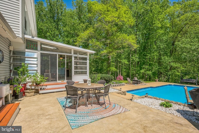 outdoor pool with outdoor dining space, a sunroom, and a patio area