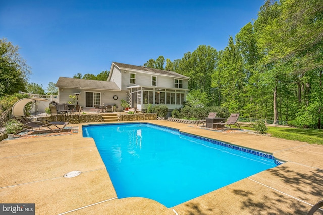 pool featuring fence, a patio, a sunroom, and a wooden deck