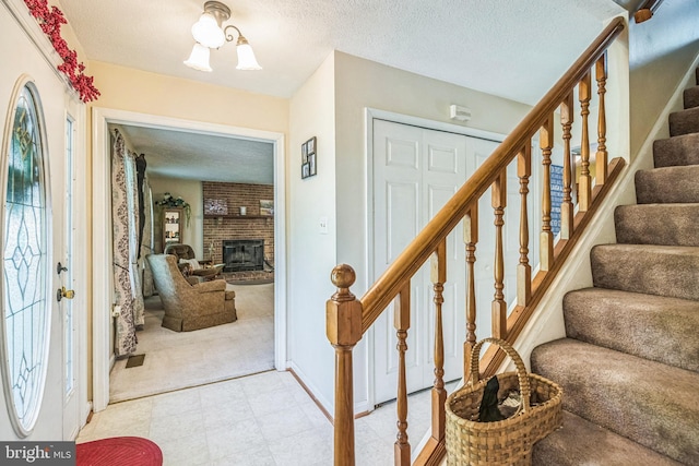 foyer with stairs, a textured ceiling, baseboards, and a fireplace