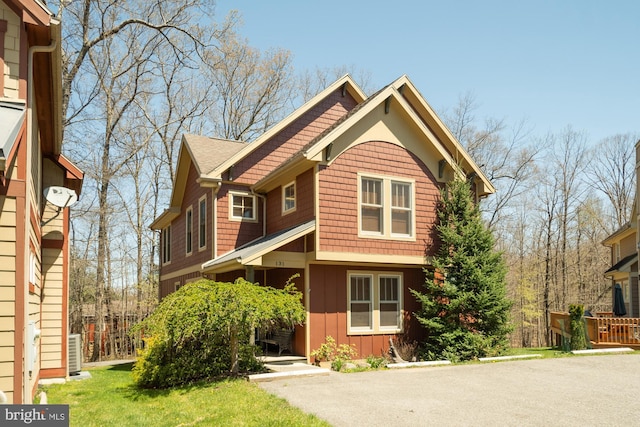 view of front of property with board and batten siding, central AC, and a front yard