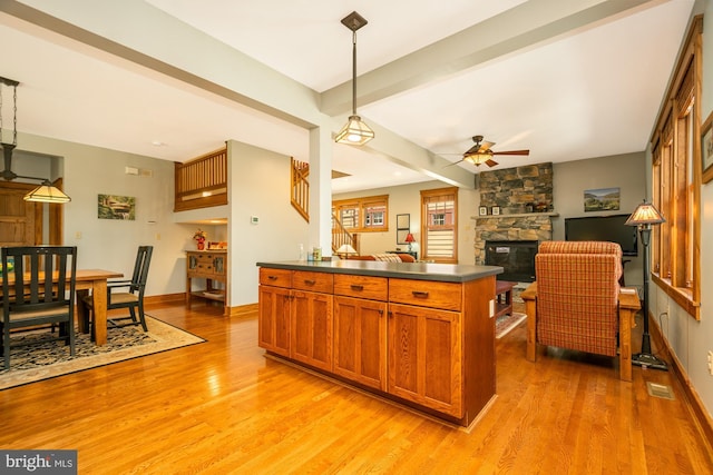 kitchen featuring light wood-style floors, dark countertops, brown cabinetry, and a fireplace