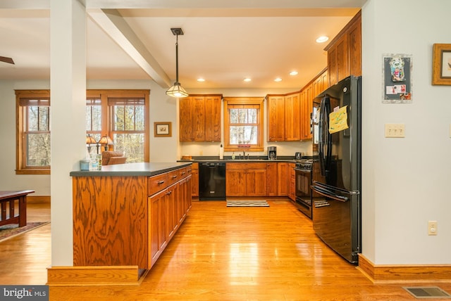 kitchen featuring visible vents, brown cabinetry, dark countertops, light wood-style floors, and black appliances