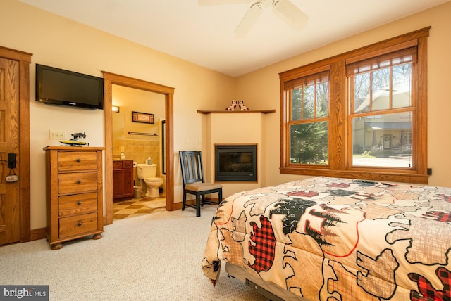 bedroom with baseboards, carpet, a ceiling fan, and ensuite bath