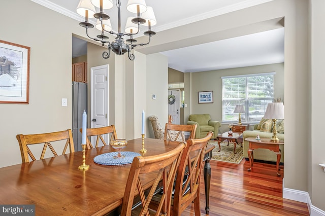dining area with a chandelier, baseboards, wood finished floors, and crown molding
