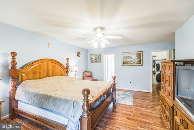 bedroom with a closet, baseboards, a walk in closet, a ceiling fan, and light wood-style flooring
