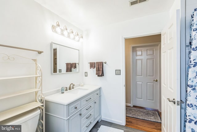 full bathroom featuring visible vents, wood finished floors, vanity, baseboards, and toilet