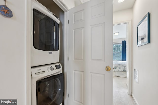 clothes washing area with stacked washer / drying machine, carpet flooring, and laundry area