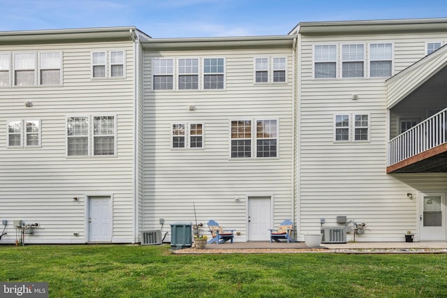 back of house with central AC unit and a yard