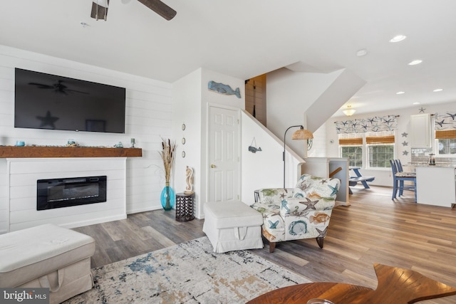 living room featuring a glass covered fireplace, ceiling fan, recessed lighting, and wood finished floors