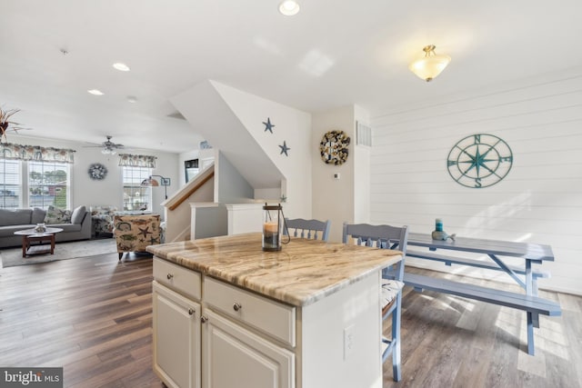 kitchen featuring recessed lighting, dark wood-style flooring, a kitchen island, and a kitchen bar