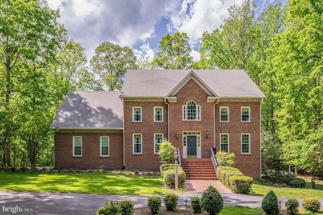 colonial-style house featuring a front yard and brick siding