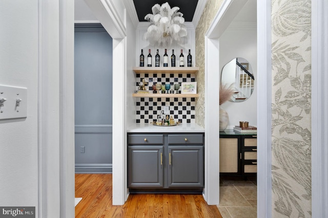 wine room with crown molding, a chandelier, a bar, and light wood-type flooring