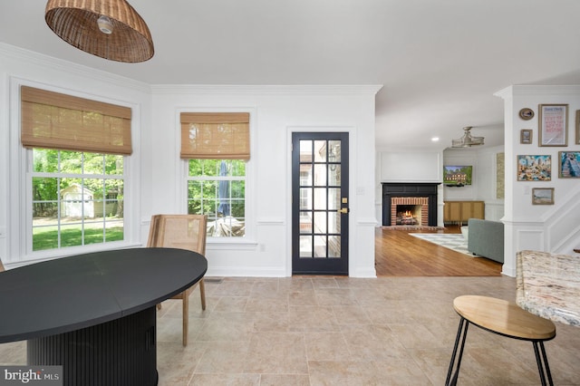 entryway with ornamental molding and a fireplace