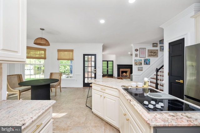 kitchen featuring a fireplace, black electric cooktop, light stone counters, open floor plan, and ornamental molding