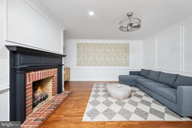 living room featuring a decorative wall, ornamental molding, light wood finished floors, and a fireplace