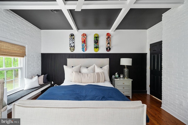 bedroom featuring beam ceiling, coffered ceiling, brick wall, and wood finished floors