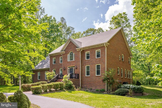 colonial house featuring brick siding and a front lawn