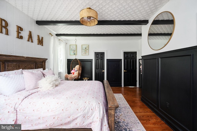 bedroom with dark wood-style floors and beam ceiling