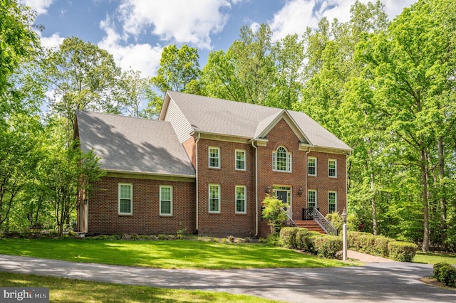 colonial-style house with brick siding and a front lawn