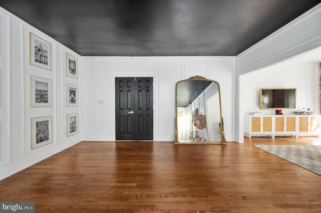 entrance foyer with wood finished floors and a decorative wall