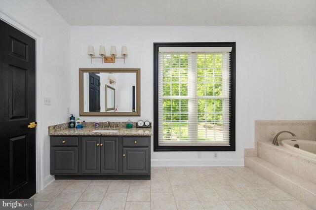 bathroom featuring a healthy amount of sunlight, vanity, tile patterned flooring, and a bath