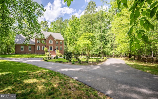 view of front of house with brick siding, aphalt driveway, and a front yard