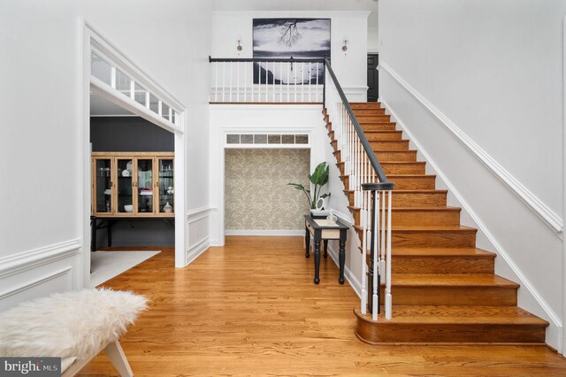 staircase with baseboards, a towering ceiling, and wood finished floors