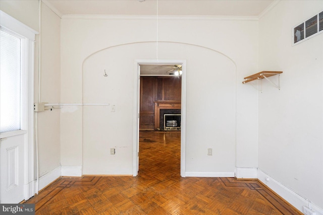 unfurnished room featuring crown molding, ceiling fan, a fireplace, baseboards, and visible vents