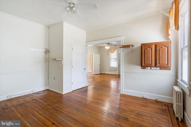 spare room featuring radiator heating unit, ceiling fan, wood-type flooring, and a healthy amount of sunlight