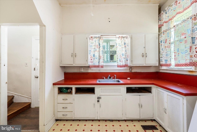 kitchen featuring white cabinetry, a sink, and light floors