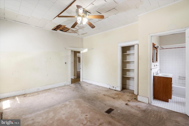unfurnished bedroom with connected bathroom, a sink, a ceiling fan, ornamental molding, and a closet