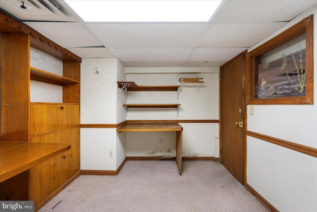 interior space with baseboards, a drop ceiling, and light colored carpet