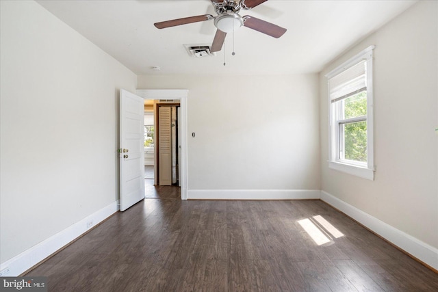 spare room featuring baseboards, visible vents, dark wood-style floors, and ceiling fan